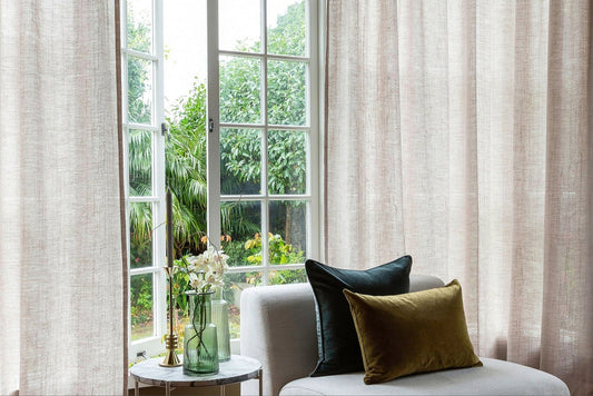 Beautiful Linen natural curtain that drapes in a rustic setting. Velvet Cushions on chair in front .Peaaceful home